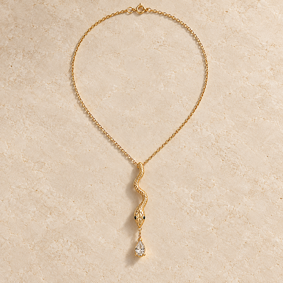 Wadjet Tear Serpent Pendant, gold-finished snake necklace with dark eyes and a clear teardrop crystal