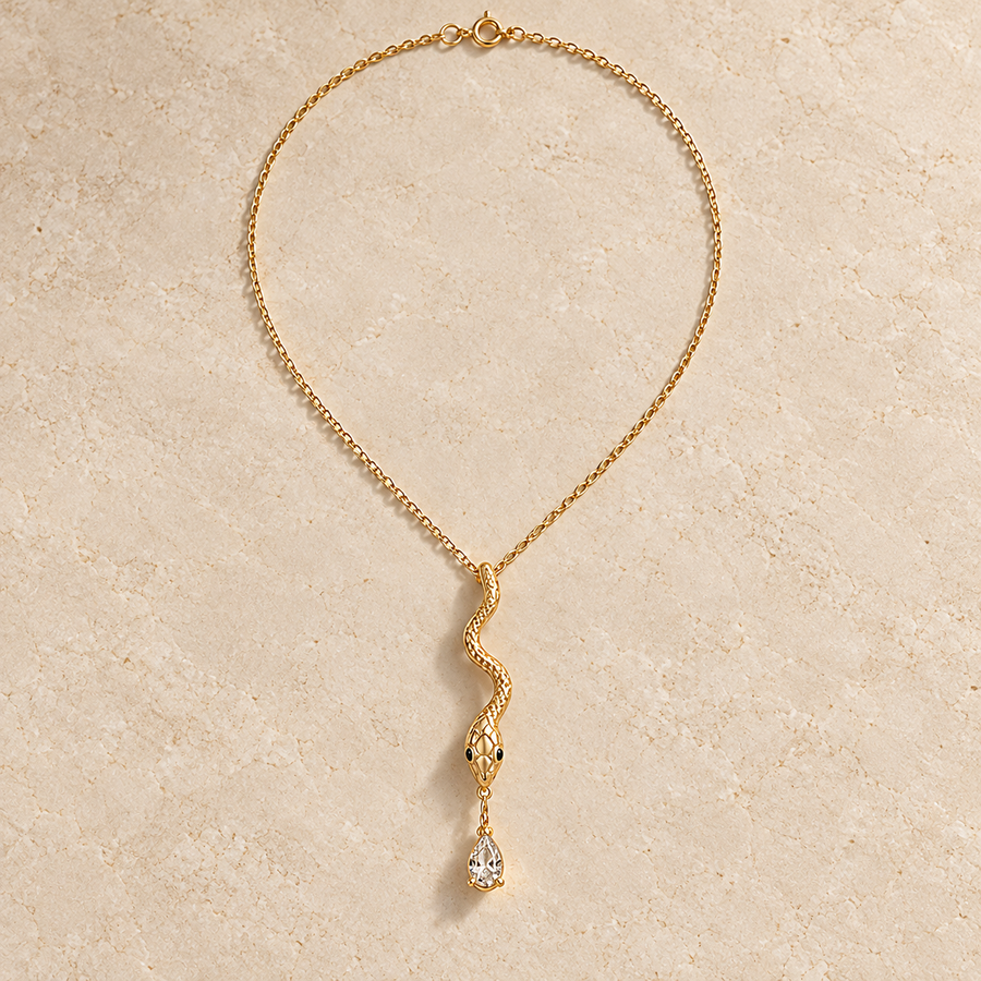 Wadjet Tear Serpent Pendant, gold-finished snake necklace with dark eyes and a clear teardrop crystal